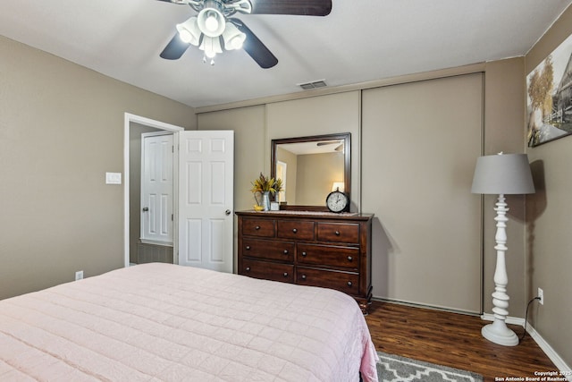 bedroom with a ceiling fan, wood finished floors, visible vents, and baseboards