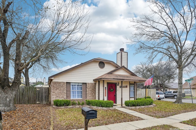 bungalow-style house with brick siding, a chimney, and fence