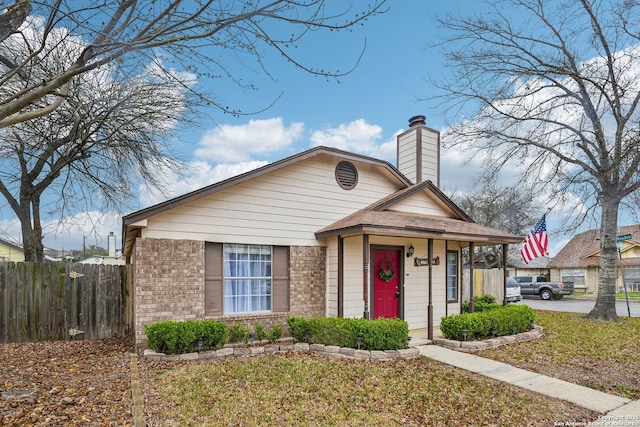 bungalow-style home featuring brick siding, a chimney, and fence