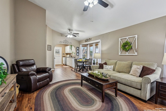 living area featuring arched walkways, vaulted ceiling, a ceiling fan, and wood finished floors