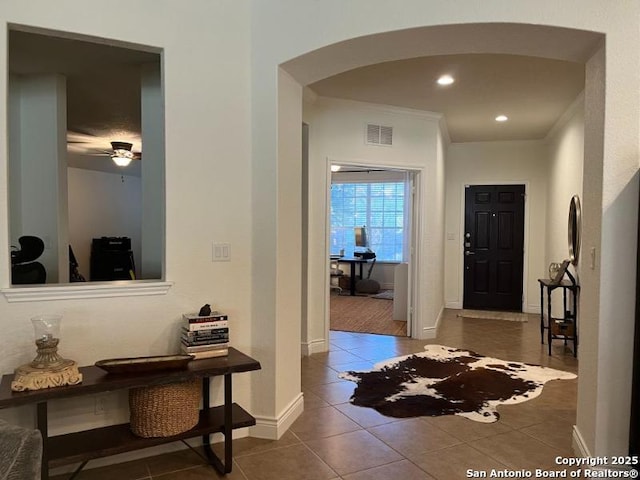 tiled foyer entrance with visible vents, ornamental molding, recessed lighting, arched walkways, and baseboards