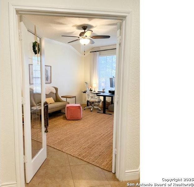 sitting room featuring light tile patterned flooring, crown molding, and a ceiling fan