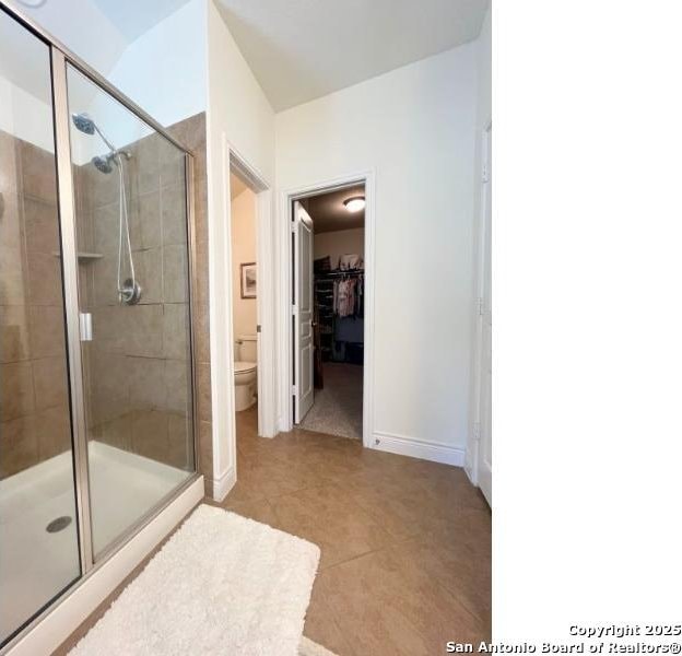 full bathroom with baseboards, toilet, a stall shower, and tile patterned flooring