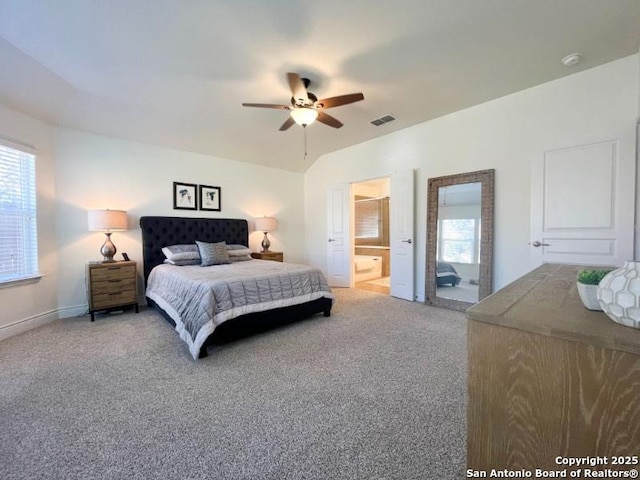 carpeted bedroom featuring visible vents, baseboards, ceiling fan, lofted ceiling, and ensuite bathroom