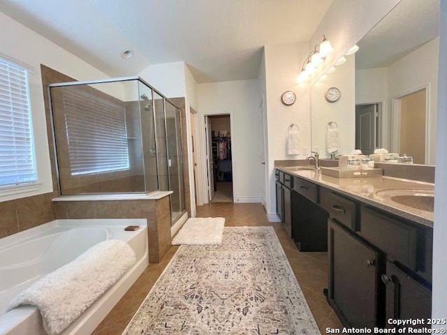 bathroom featuring tile patterned floors, a stall shower, a sink, and a bath