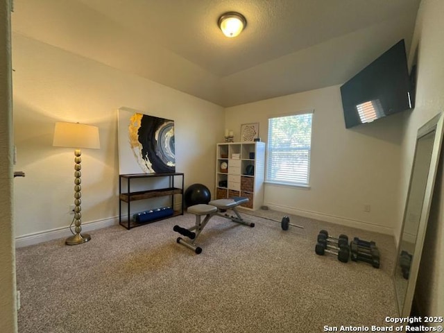 exercise room featuring vaulted ceiling, carpet flooring, and baseboards