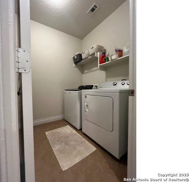 washroom with baseboards, visible vents, laundry area, washer and dryer, and tile patterned floors