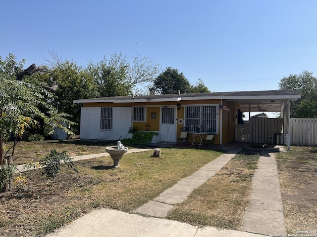 view of front of house with a front lawn, fence, brick siding, and a carport