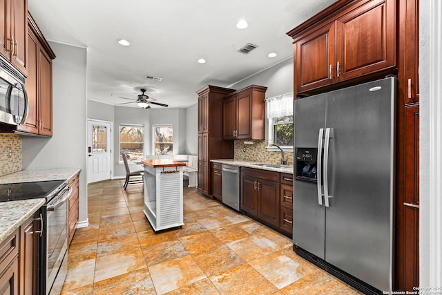 kitchen featuring a ceiling fan, visible vents, a sink, decorative backsplash, and stainless steel appliances