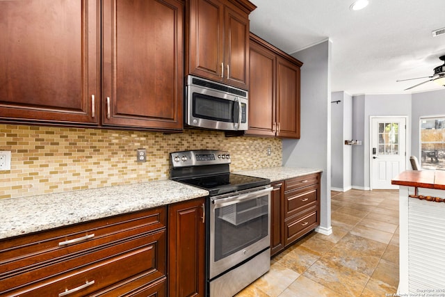 kitchen featuring light stone counters, a ceiling fan, baseboards, appliances with stainless steel finishes, and backsplash