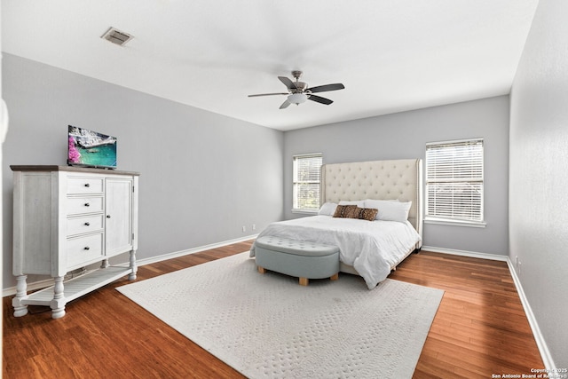 bedroom with a ceiling fan, wood finished floors, visible vents, and baseboards