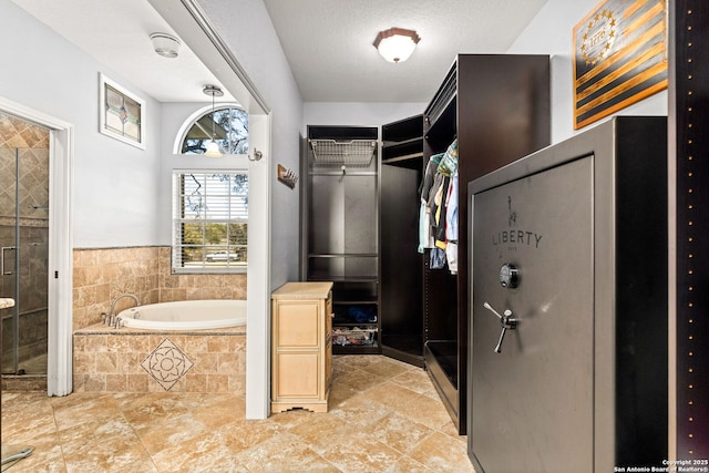 bathroom with a stall shower, a textured ceiling, a walk in closet, and a garden tub