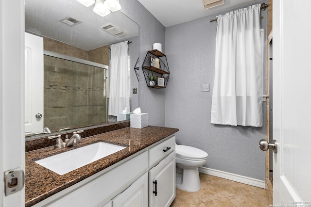 full bathroom with a tile shower, visible vents, toilet, and a textured wall