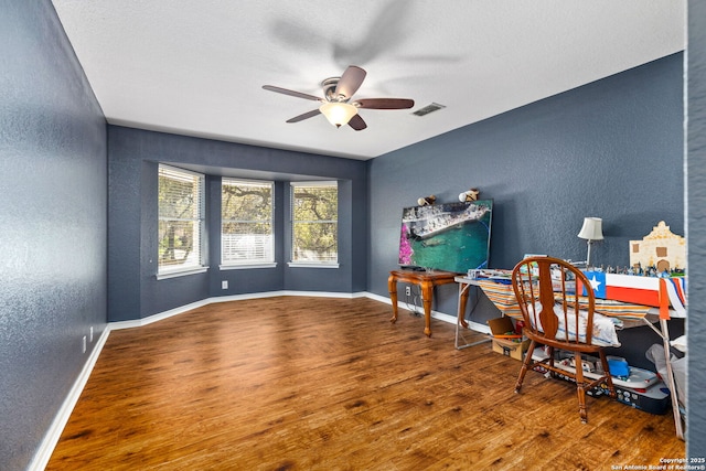 office space featuring ceiling fan, wood finished floors, baseboards, and a textured wall