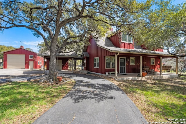 chalet / cabin with driveway, a front yard, board and batten siding, and a shingled roof