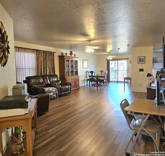 living area featuring visible vents, a textured ceiling, wood finished floors, and a ceiling fan