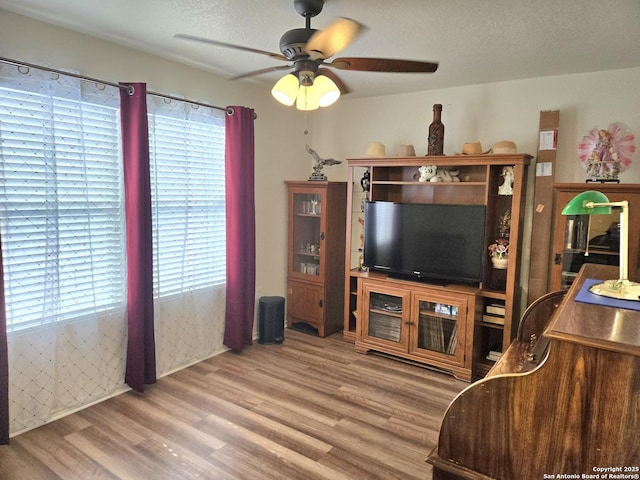 living area with a healthy amount of sunlight, a textured ceiling, a ceiling fan, and wood finished floors