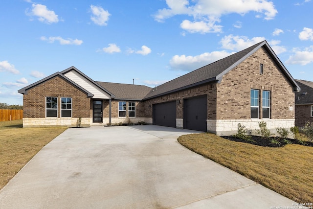 view of front of home featuring a front yard, fence, driveway, an attached garage, and brick siding