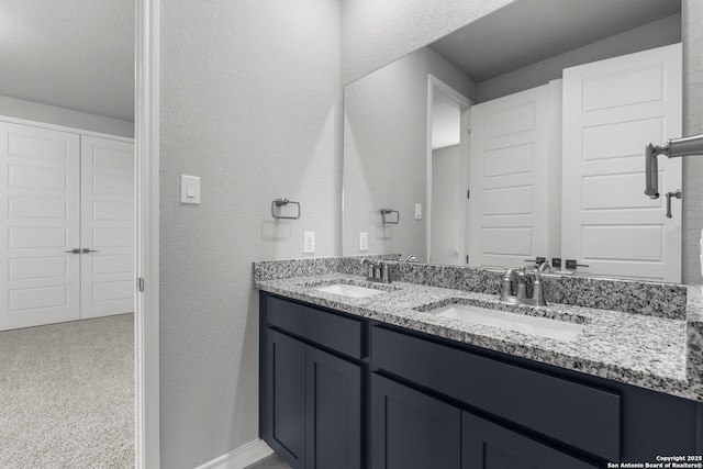 bathroom featuring double vanity, a textured wall, and a sink