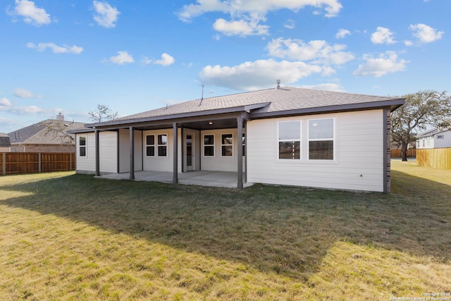 back of house with a lawn, a shingled roof, a patio, and fence