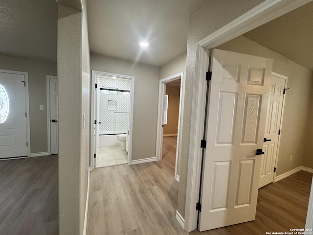 corridor featuring baseboards and light wood finished floors