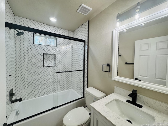 bathroom featuring visible vents, toilet, a textured wall, shower / bath combination with glass door, and vanity