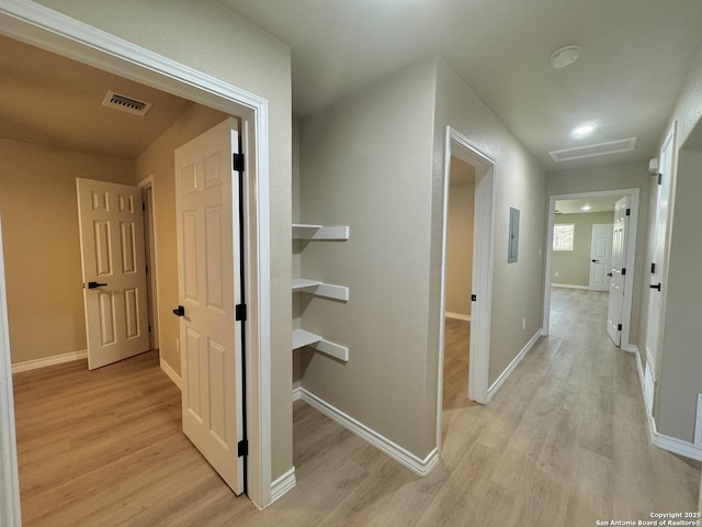 hall with light wood finished floors, visible vents, attic access, and baseboards