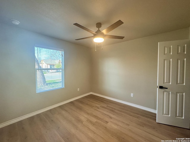 spare room featuring ceiling fan, baseboards, and wood finished floors