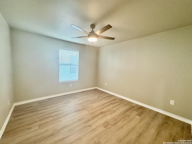 empty room with a ceiling fan, wood finished floors, baseboards, and a textured ceiling