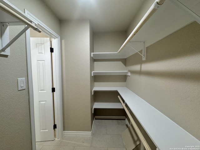 walk in closet with light tile patterned floors