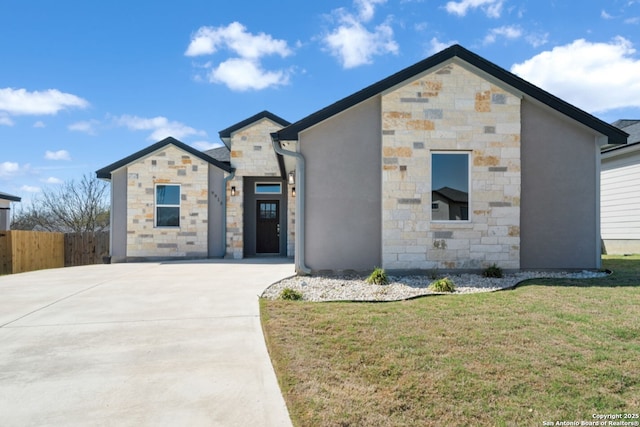 view of front of house featuring fence, a front yard, stucco siding, stone siding, and driveway