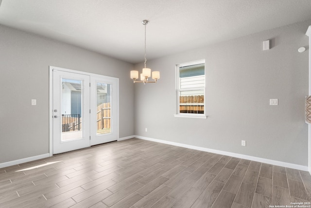 empty room featuring baseboards, an inviting chandelier, and wood finished floors