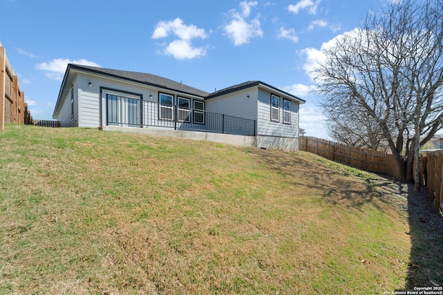 rear view of house with a yard and a fenced backyard