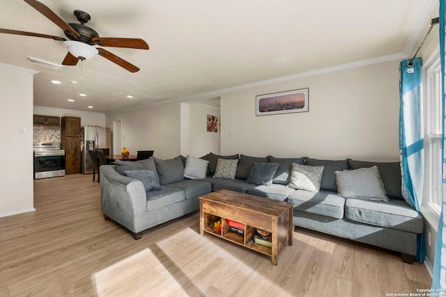 living area with visible vents, light wood-style flooring, a ceiling fan, and ornamental molding