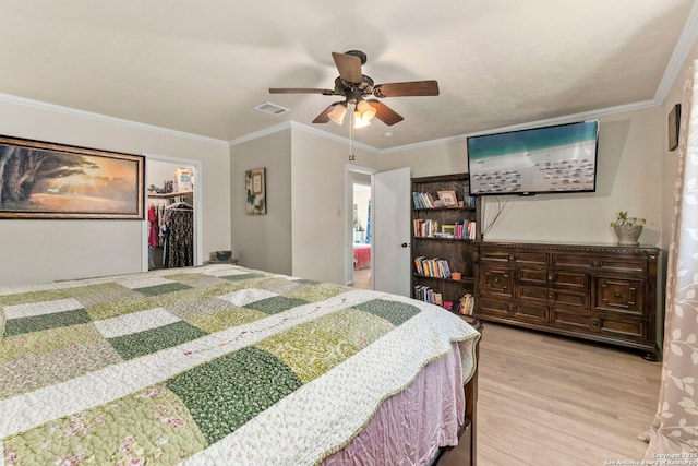 bedroom with visible vents, ornamental molding, a ceiling fan, wood finished floors, and a closet