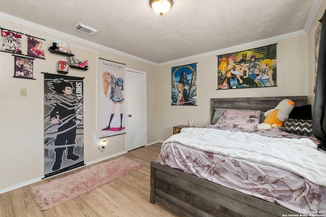 bedroom with crown molding, wood finished floors, visible vents, and baseboards