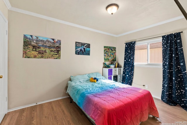 bedroom with ornamental molding, baseboards, and wood finished floors