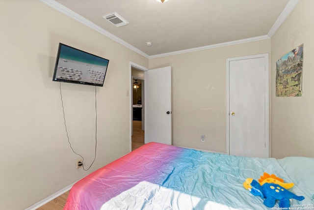 bedroom featuring visible vents, wood finished floors, baseboards, and ornamental molding