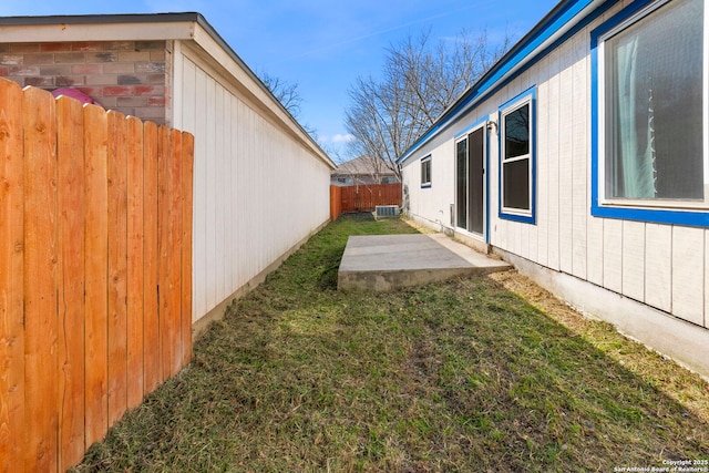 view of yard with central AC unit, a fenced backyard, and a patio