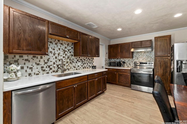 kitchen featuring visible vents, under cabinet range hood, light wood-type flooring, appliances with stainless steel finishes, and a sink