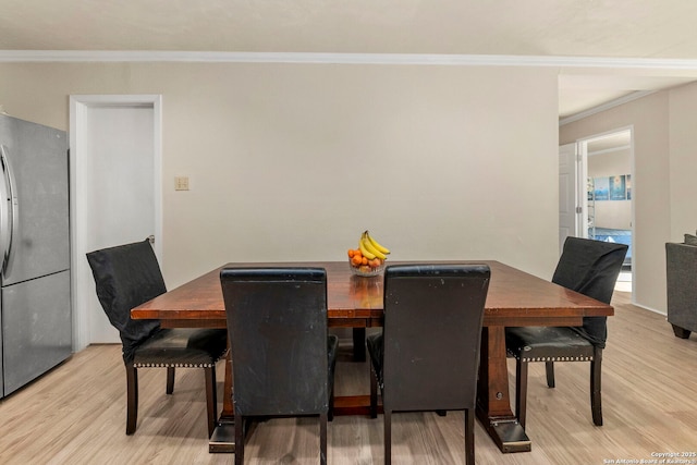 dining area featuring light wood-style floors and crown molding