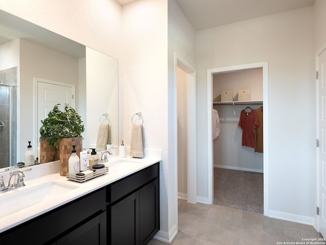 bathroom featuring a spacious closet, a shower stall, double vanity, and a sink
