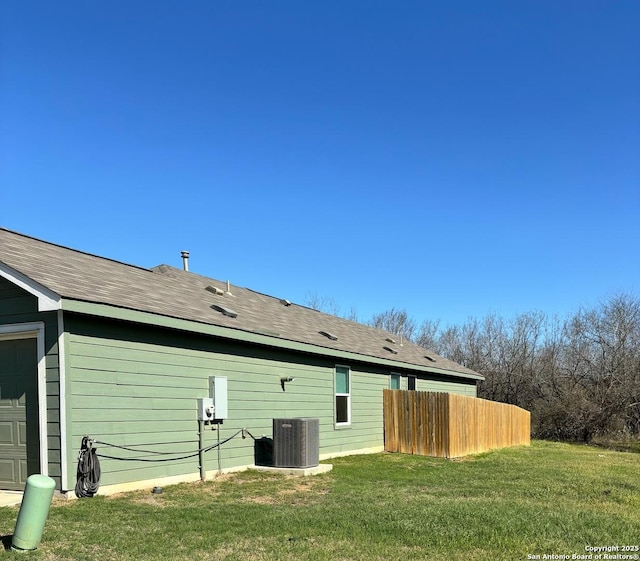 back of property with central air condition unit, a yard, fence, and a garage