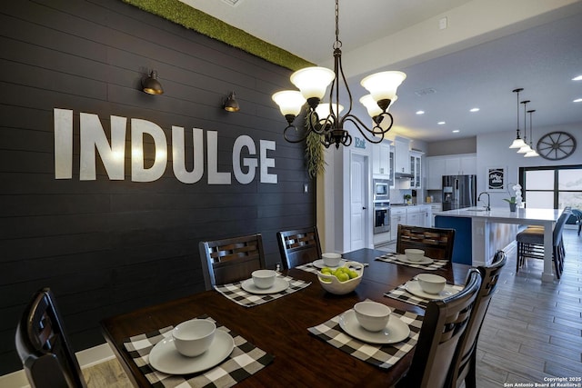 dining room with recessed lighting, an inviting chandelier, wood finished floors, and wood walls