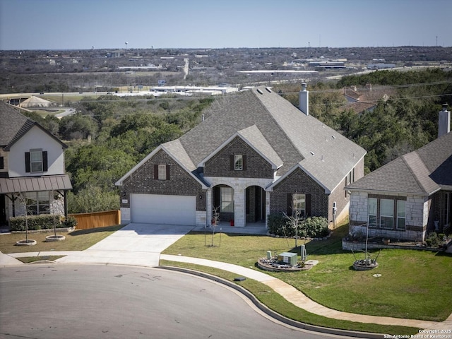 view of front facade featuring brick siding, a shingled roof, a front yard, a garage, and driveway