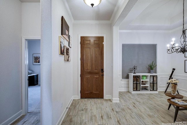 entryway featuring ornamental molding, baseboards, an inviting chandelier, and wood finished floors