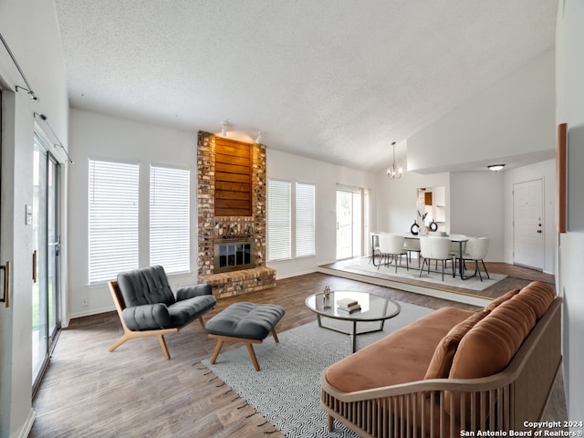 living room with wood finished floors, a notable chandelier, a fireplace, and a textured ceiling