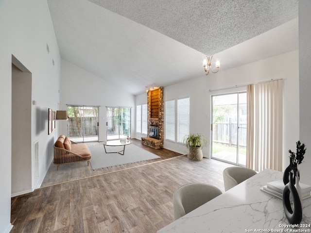 unfurnished living room with a brick fireplace, a notable chandelier, wood finished floors, and a wealth of natural light