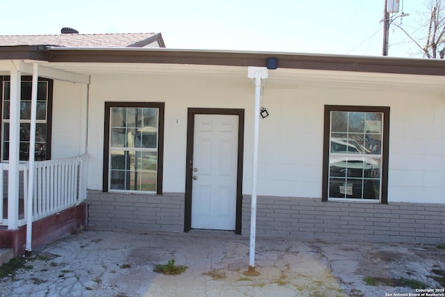 entrance to property featuring brick siding and a porch