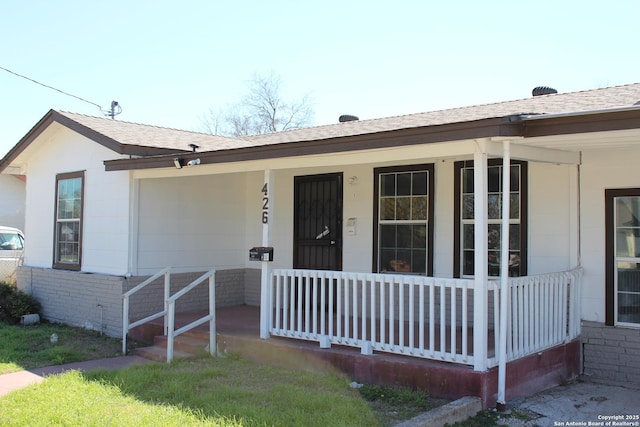 view of front of property featuring brick siding, a porch, and roof with shingles